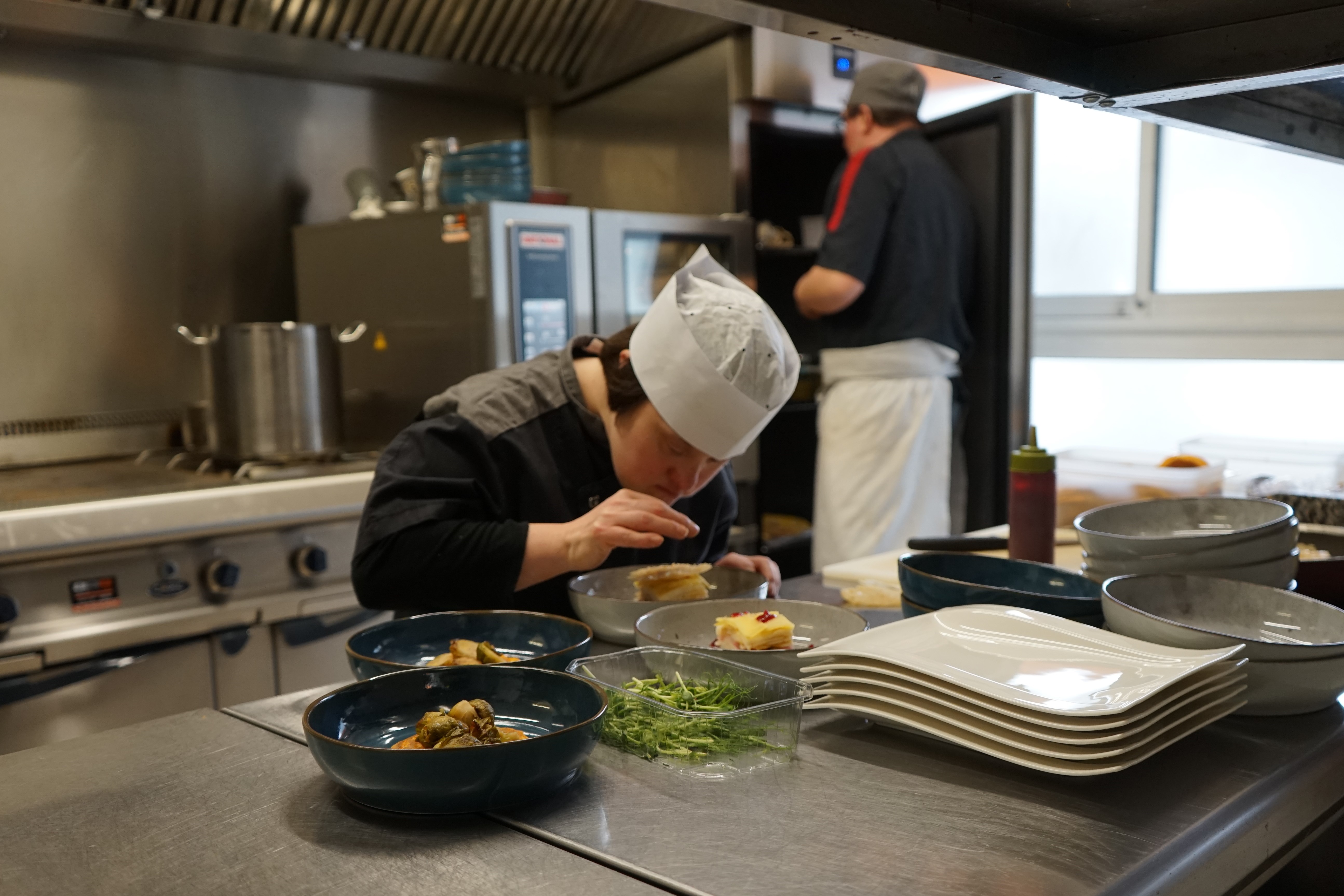 Une cuisinière décore un plat